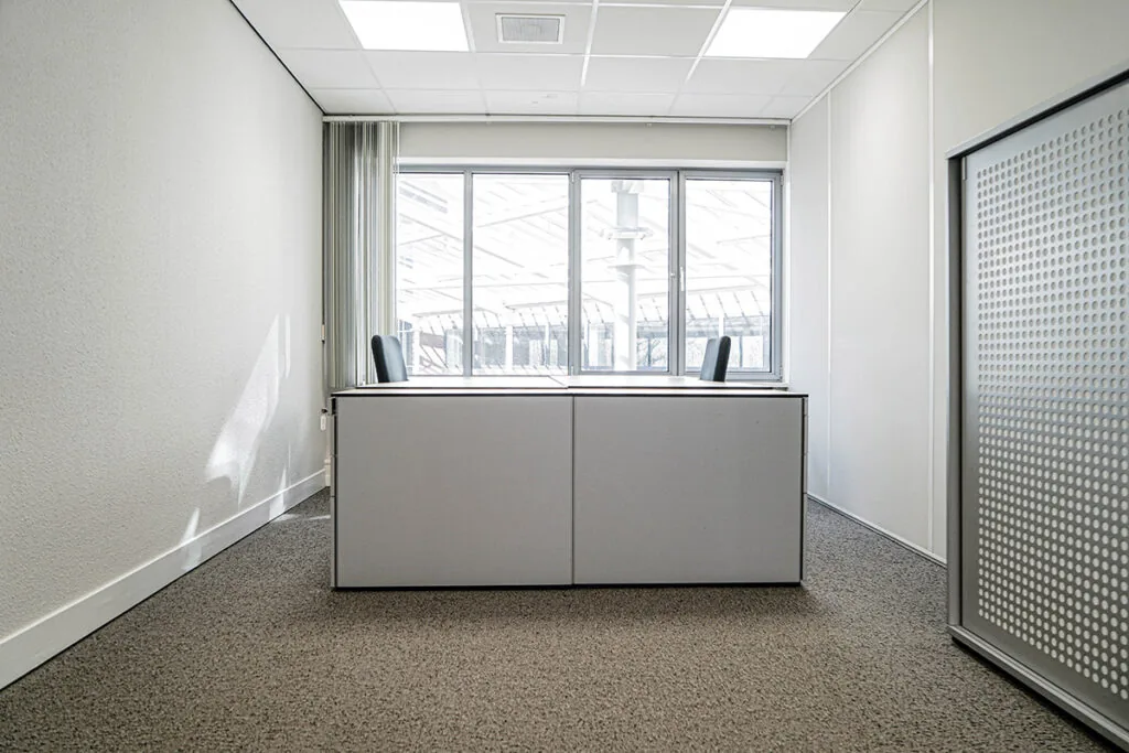 Licht en modern kantoor met twee bureaustoelen aan een groot raam aan de Burgemeester van Karnebeeklaan.